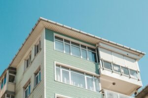 Low angle view of a modern apartment building exterior with glass windows under a clear blue sky.